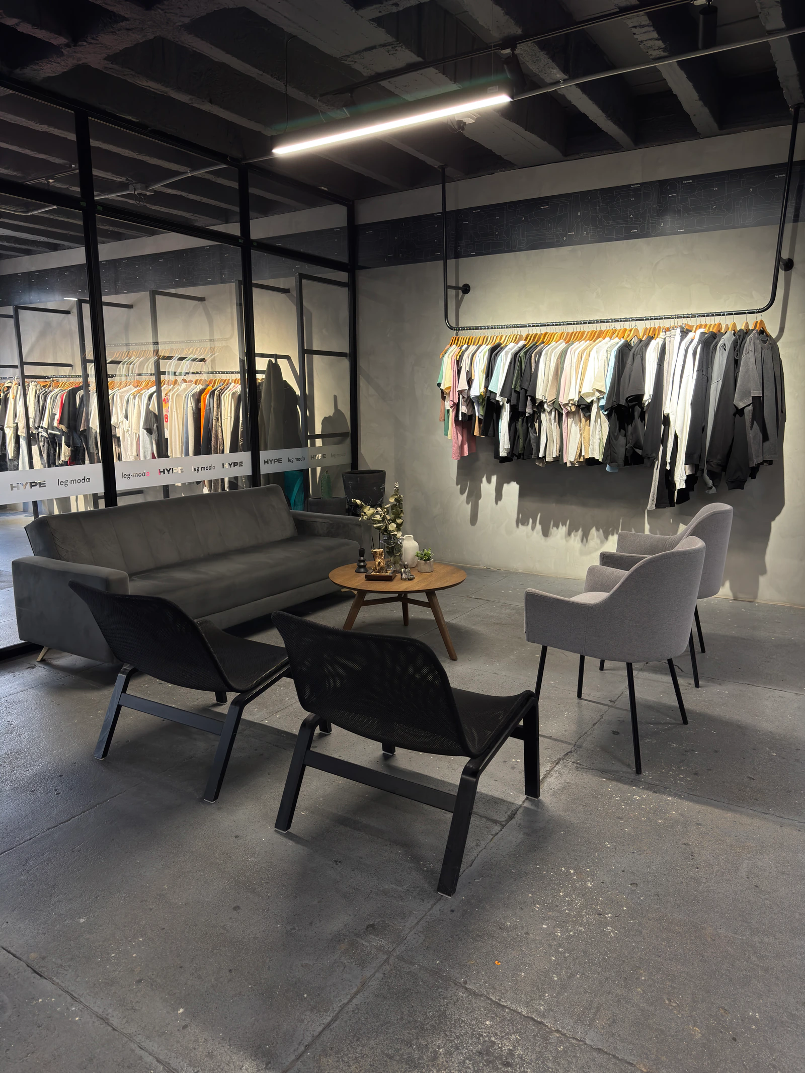 Zona de espera de la tienda Classior, con sofá, sillas y percha de camisetas